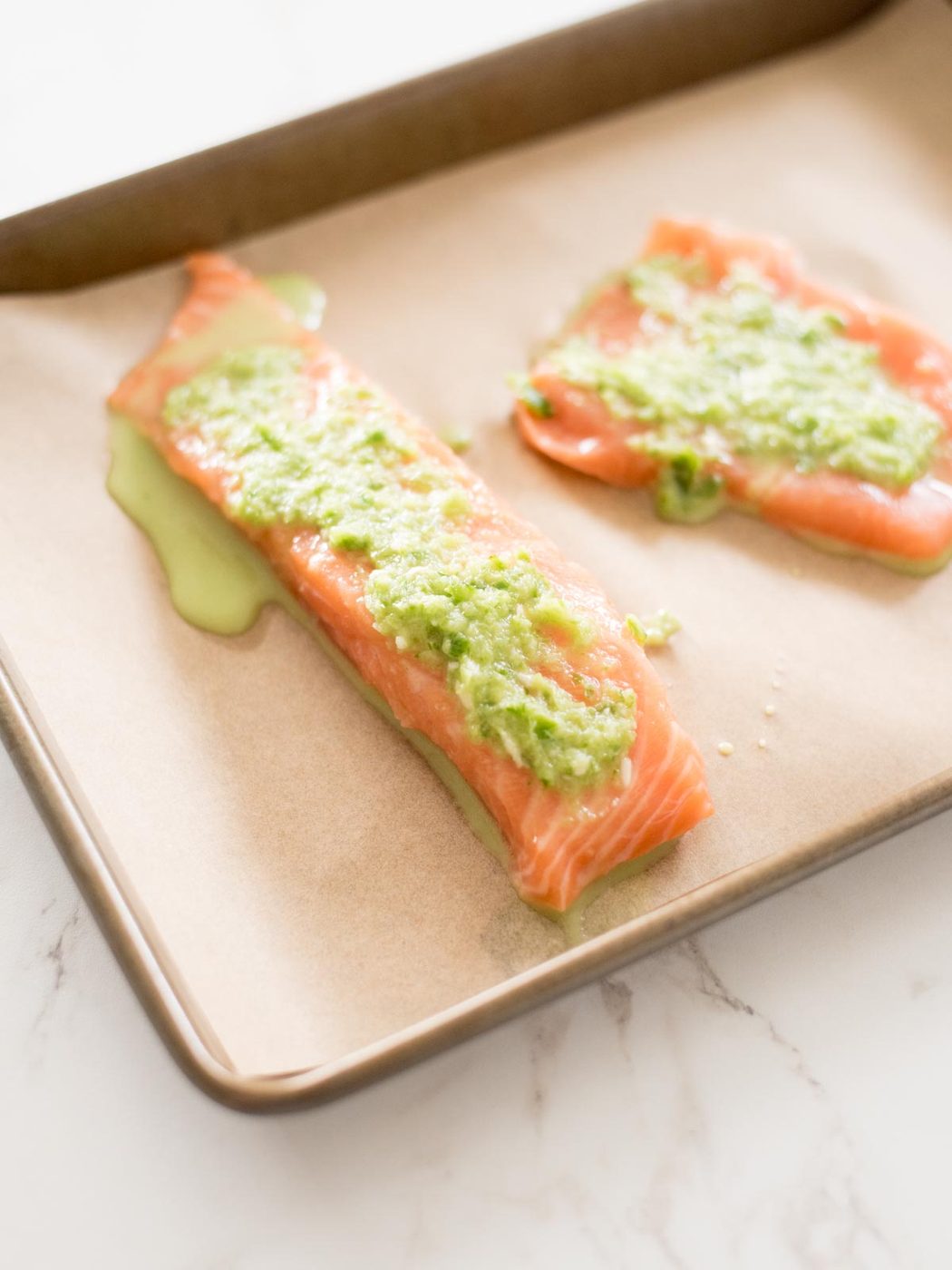 honey jalapeno lime mix on salmon filets on a parchment lined baking sheet