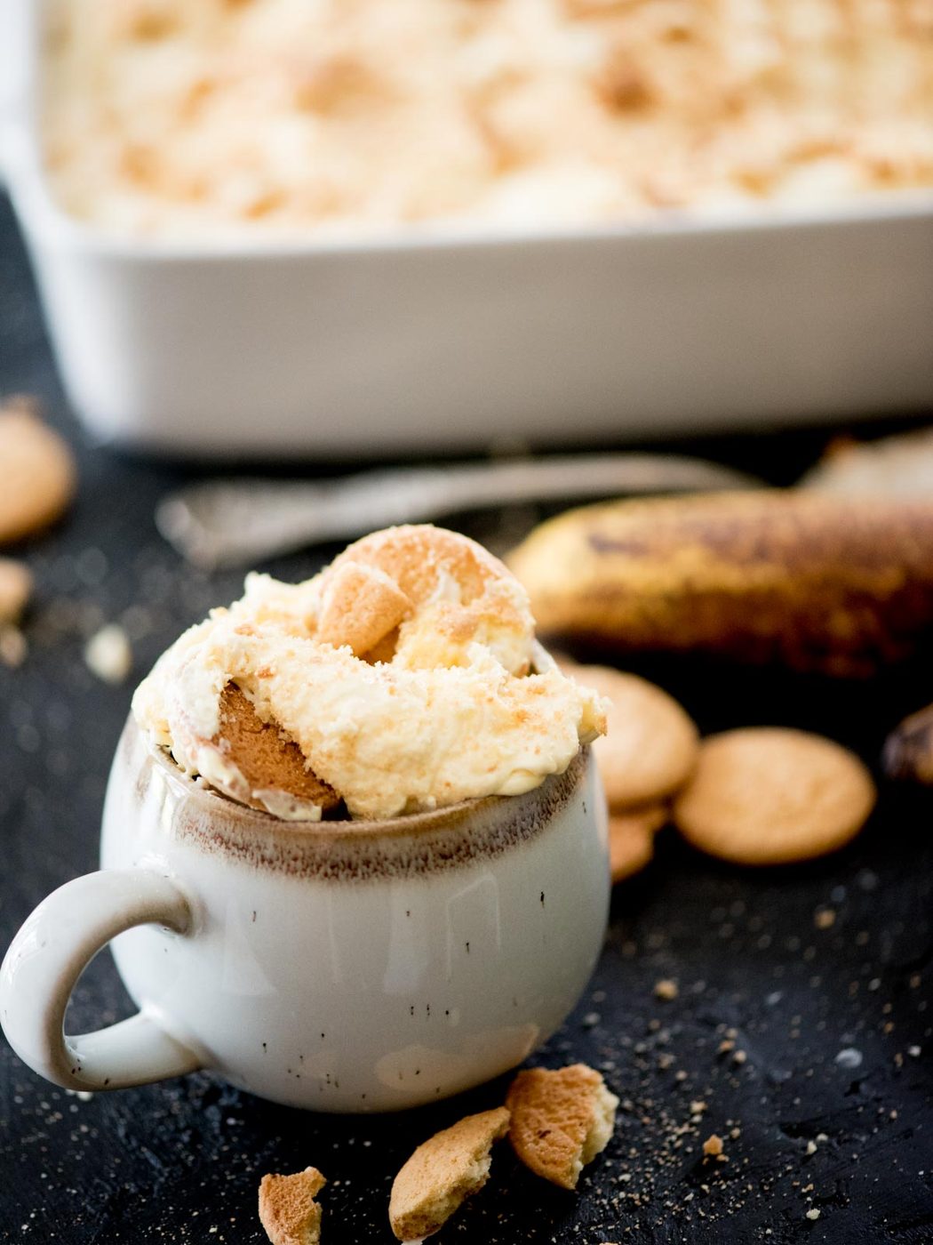 banana pudding in a mug with crushed vanilla wafers surrounding