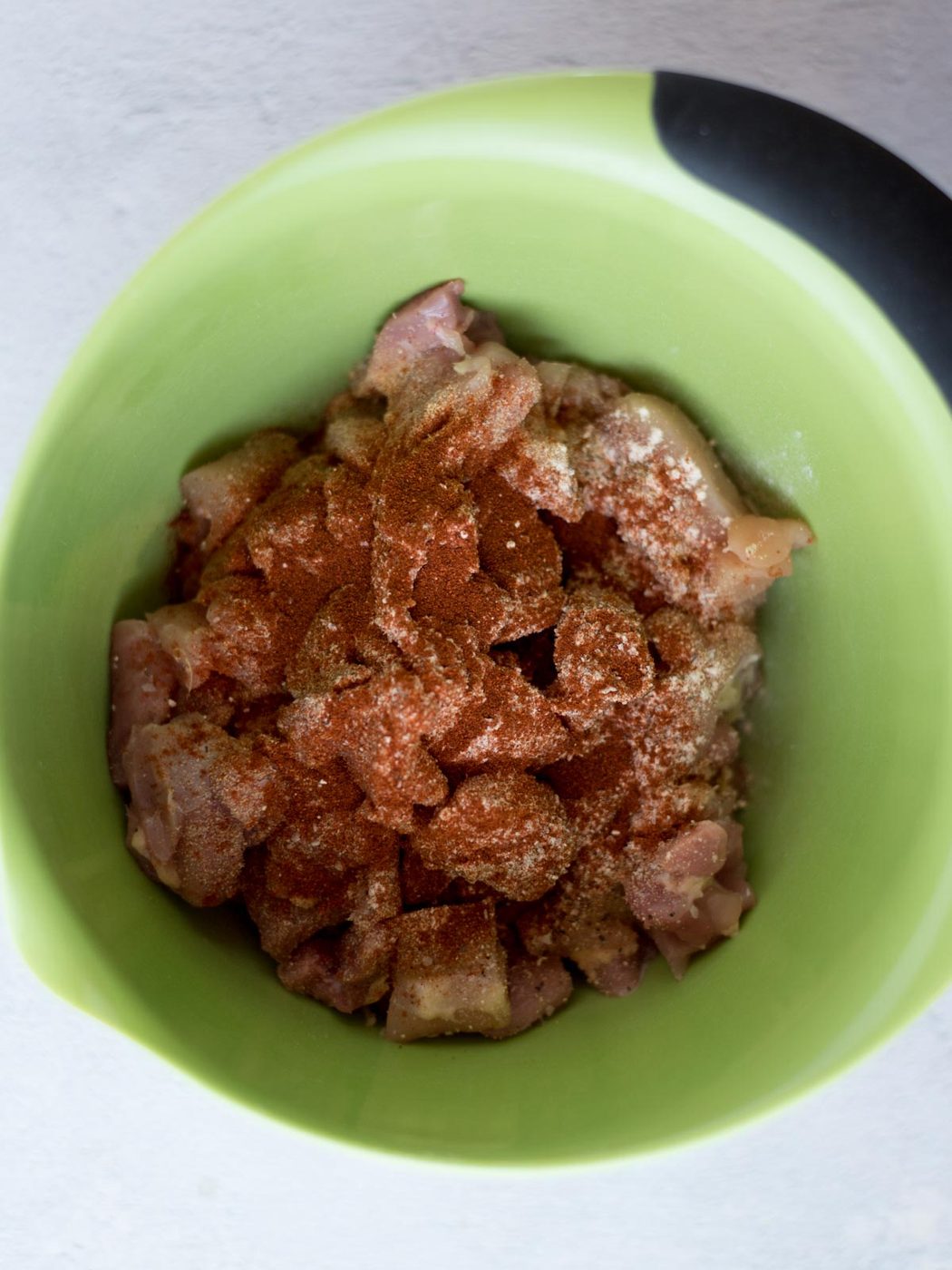 chopped chicken breast chunks in a mixing bowl with seasonings