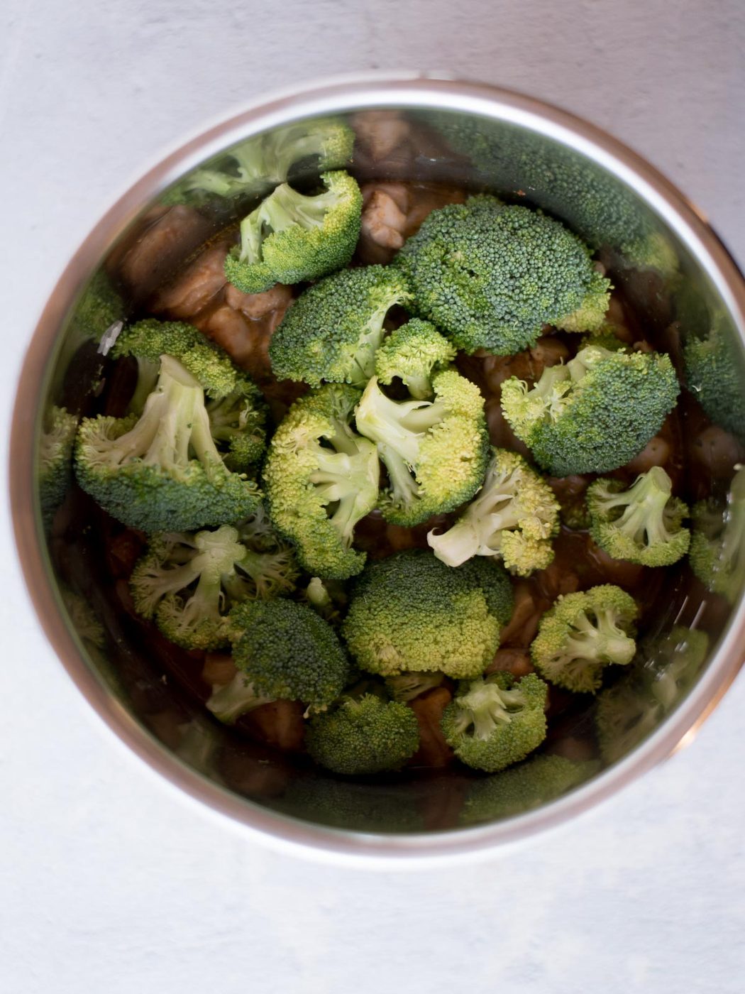 broccoli added to the instant pot liner on top of the chicken and rice