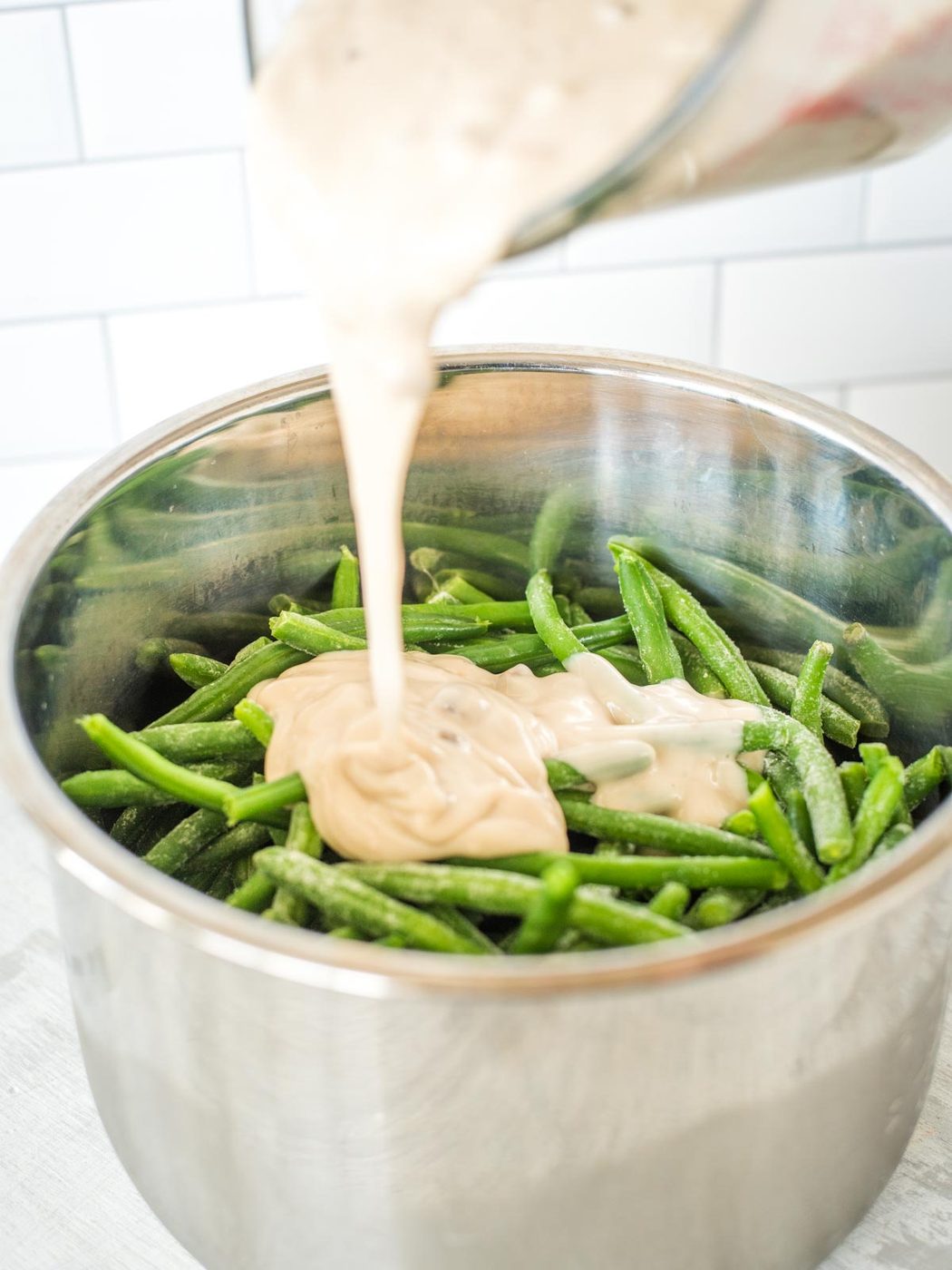 green bean casserole mix being poured into instant pot sleeve