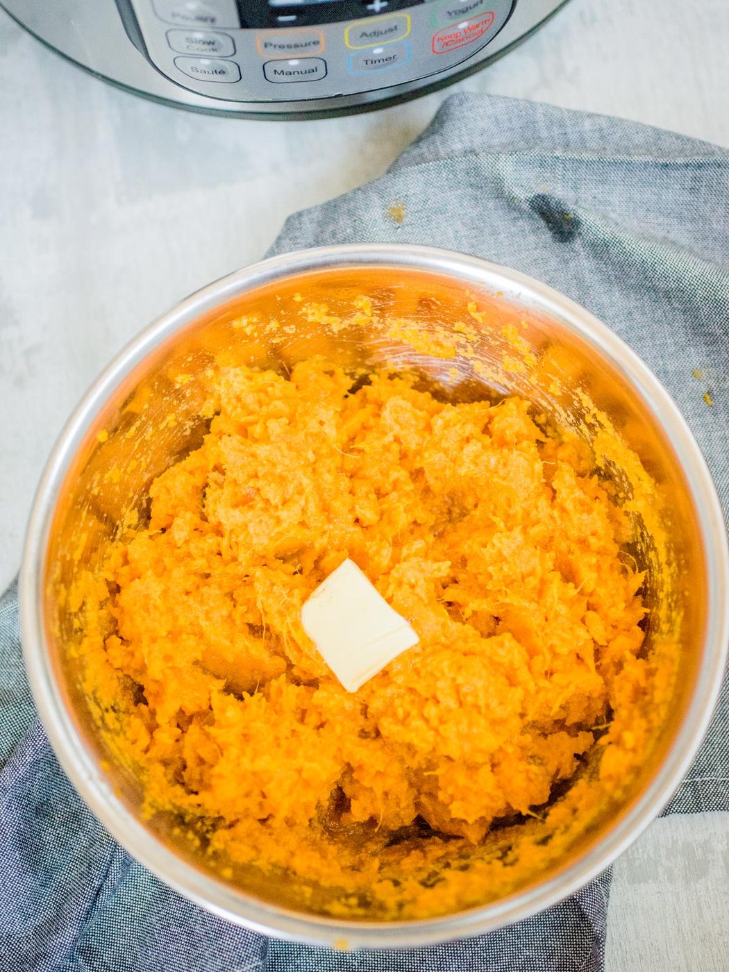 mashed sweet potatoes in a stainless bowl topped with butter