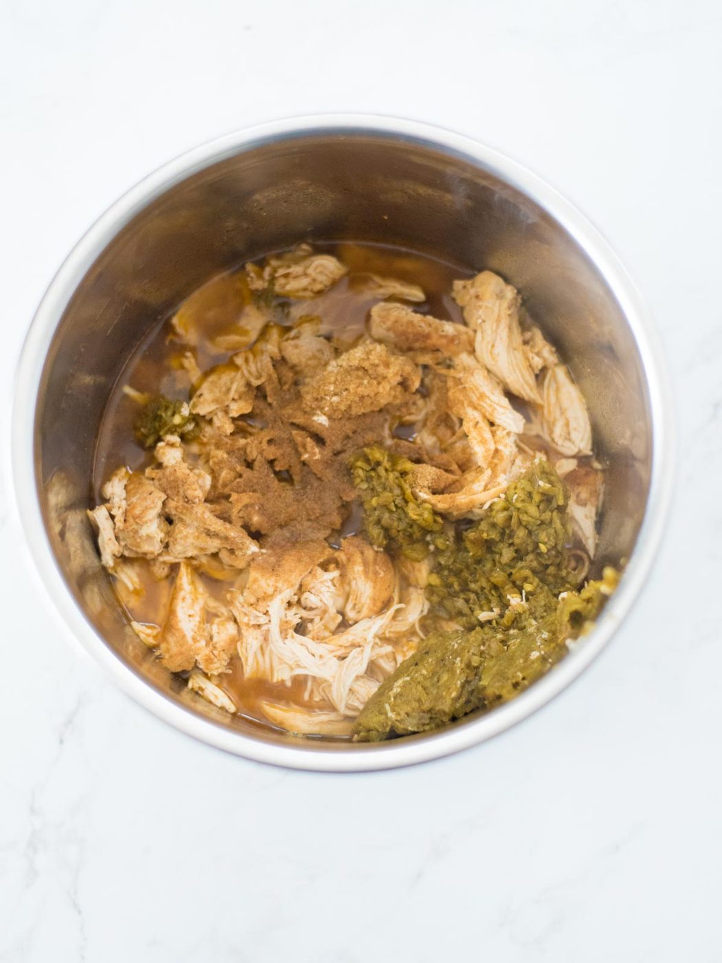 green chiles and seasonings added to shredded chicken and broth in an instant pot