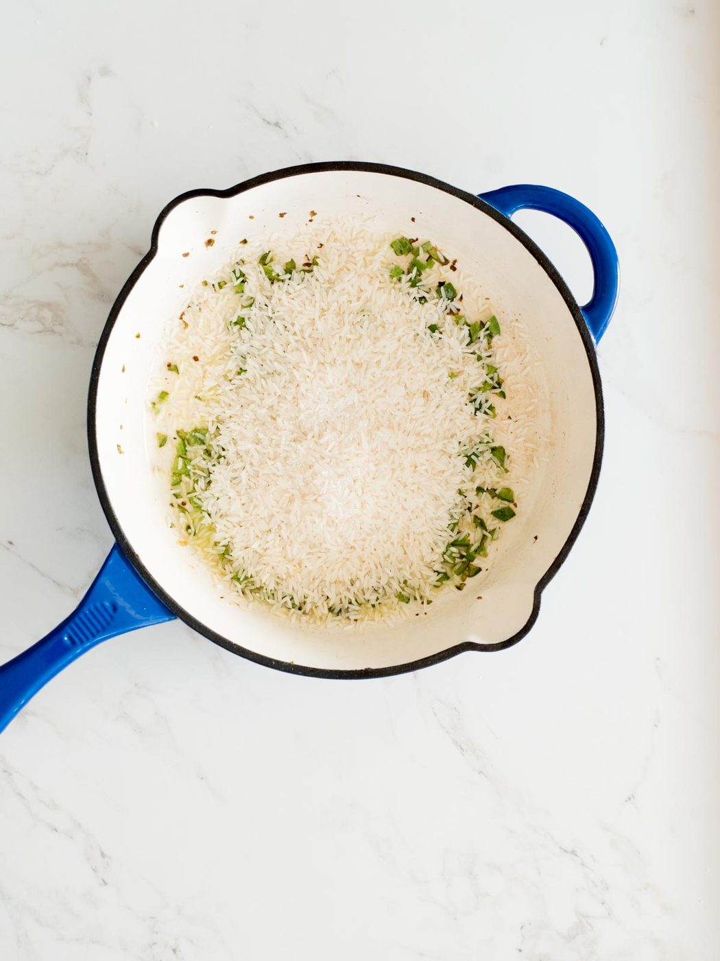 seasoning added to rice in a skillet
