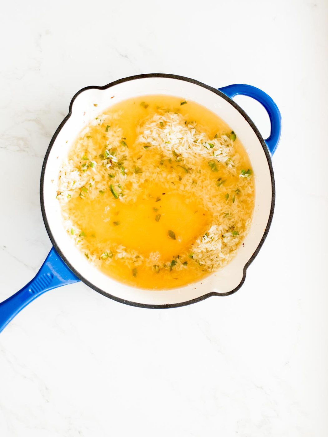 broth in skillet with rice and jalapeno