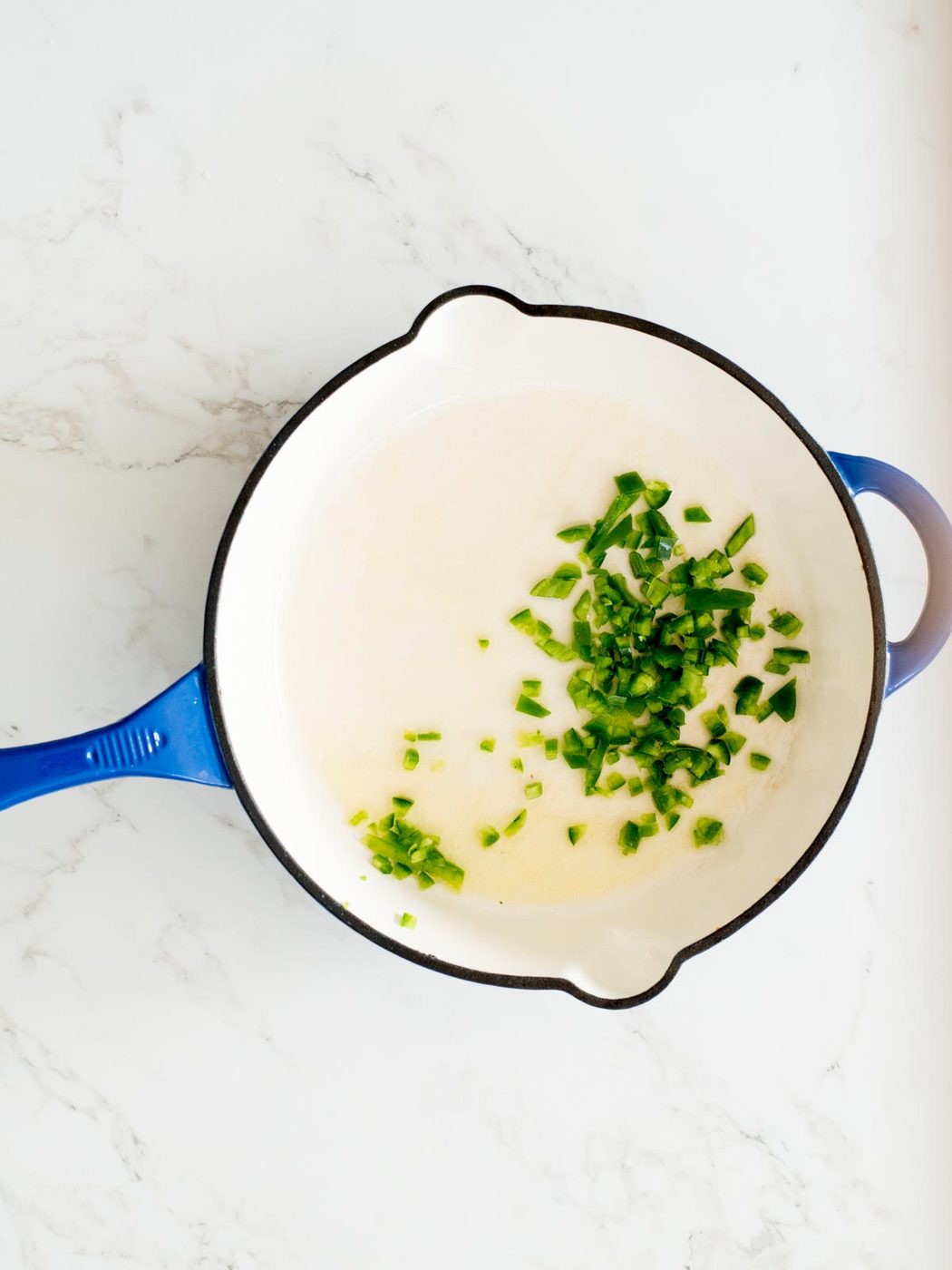 chopped jalapeno added to an enamel cast iron skillet with butter