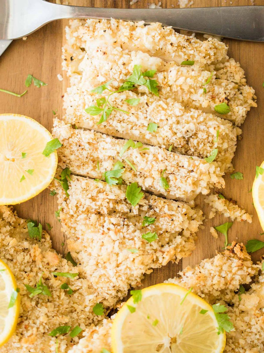 overhead of sliced lemon pepper chicken with lemons and parsley