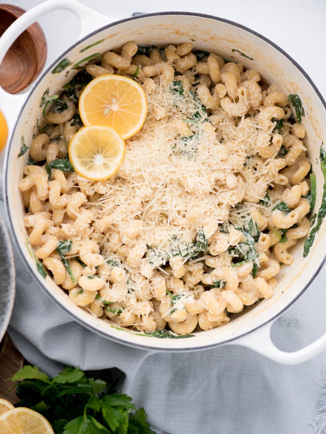 Top view of a dutch oven with parmesan cheese over lemon ricotta pasta, garnished with lemon slices.