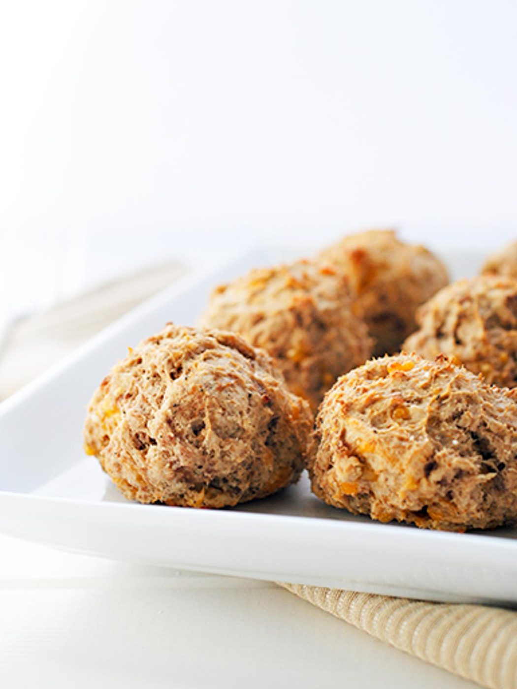 Side view of lighter sausage balls sitting on a white serving plate.