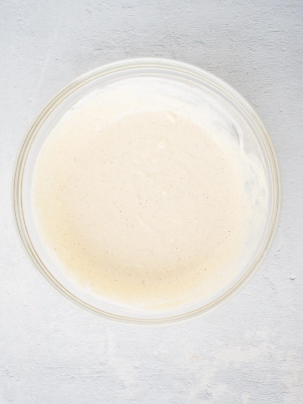 Dressing for macaroni salad in a glass mixing bowl.