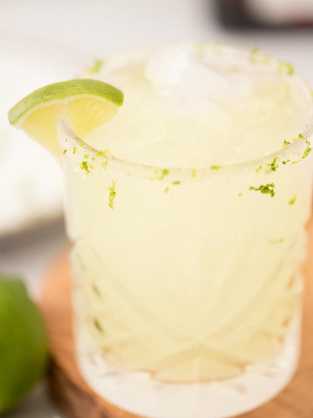 margarita on the rocks in a salt rimmed glass with a lime wedge and lime zest