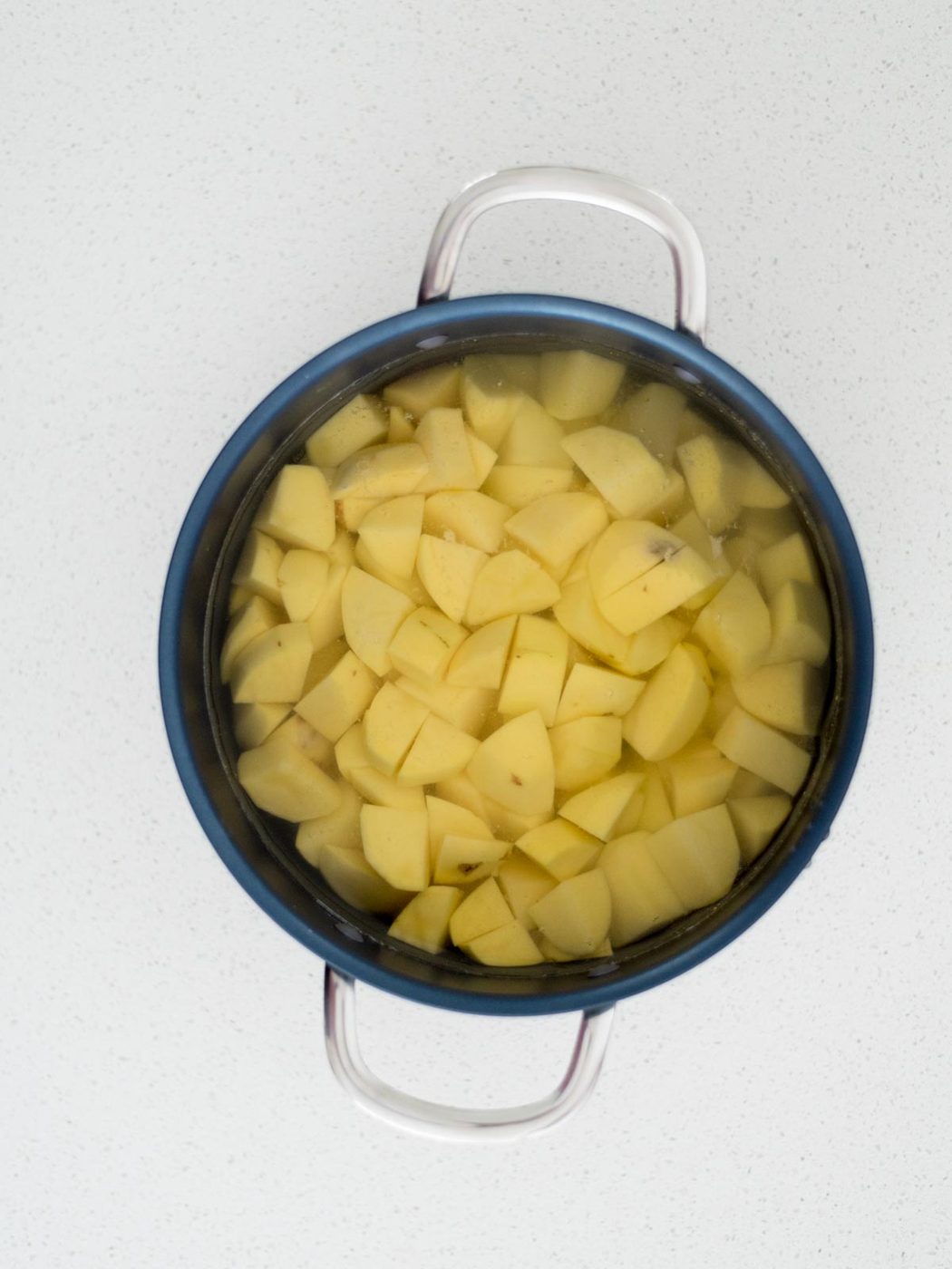 Raw potatoes added to a sauce pan covered with water.