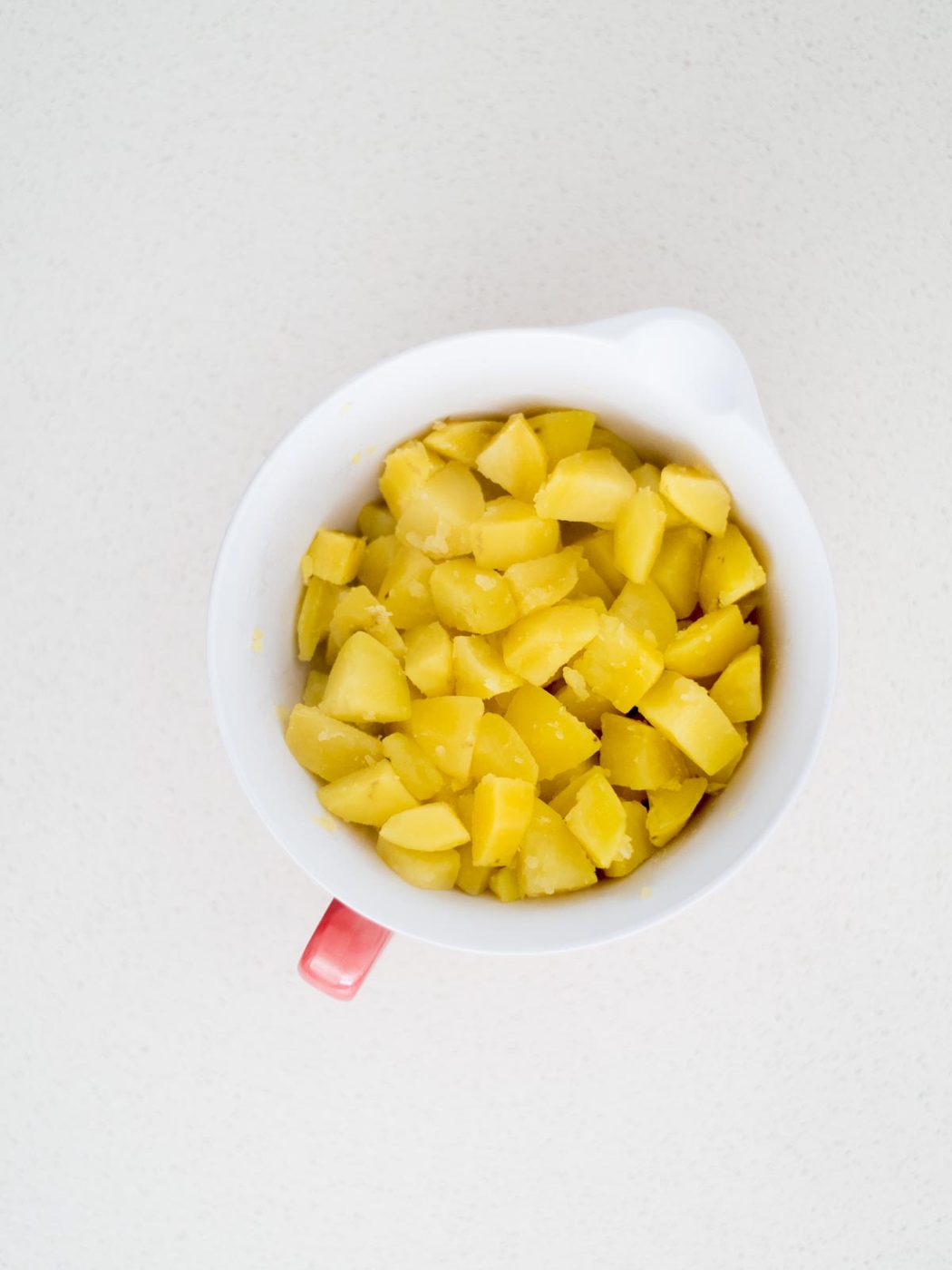 Mixing bowl with cooked cut up potato pieces.