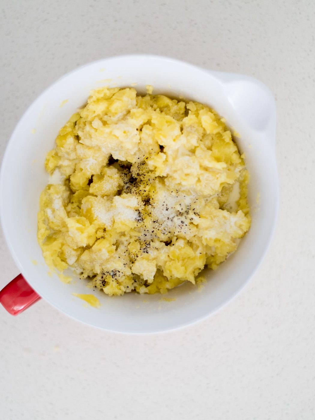 Mixing bowl with seasoning added to the potatoes and butter as its being mashed.