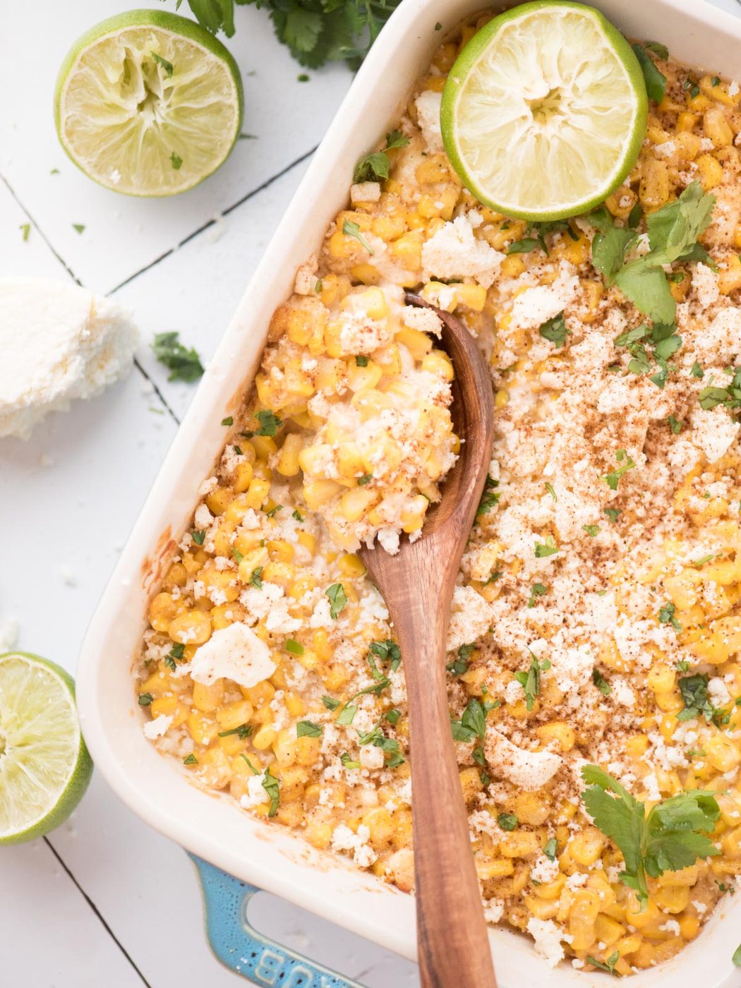 Wooden spoonful of street corn casserole in a baking dish.