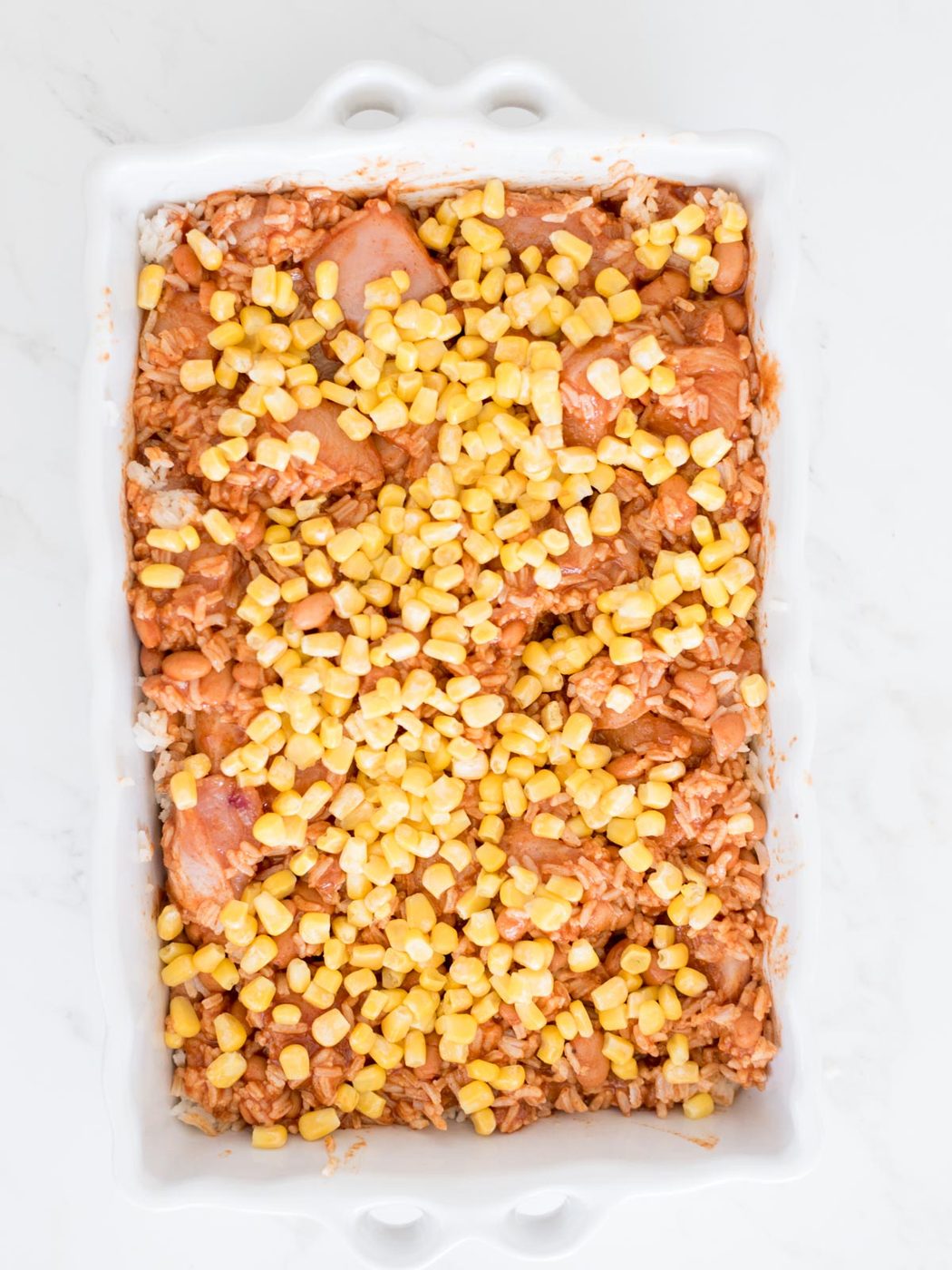 corn sprinkled over the top of the chicken rice and beans mix