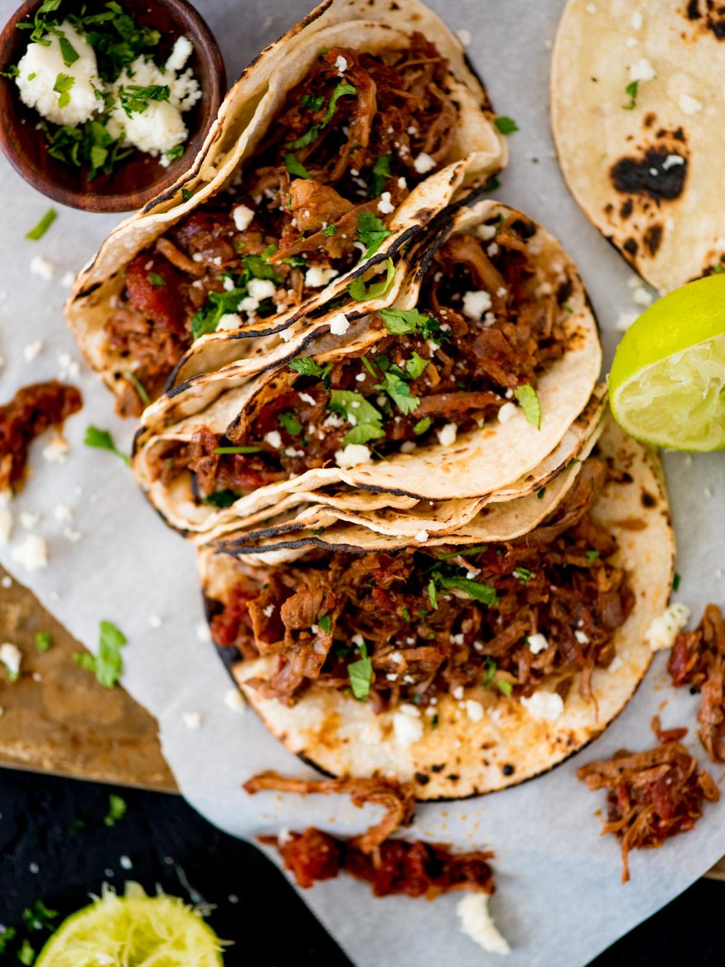 mexican shredded beef inside tacos topped with cilantro and queso fresco