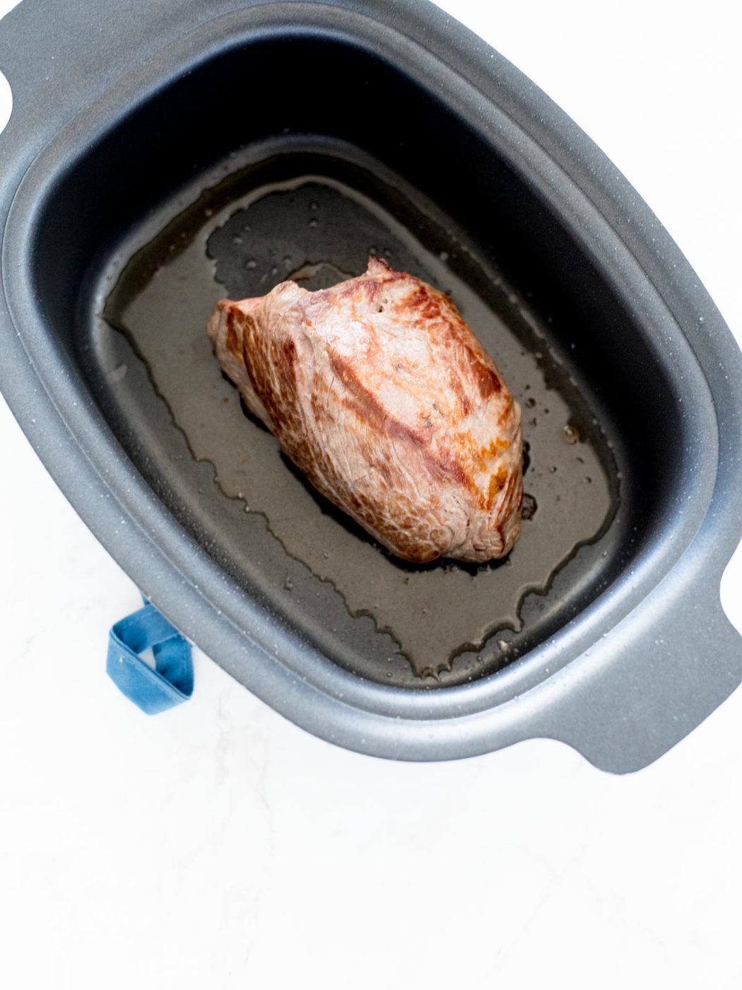 beef roast seared and sitting in crockpot