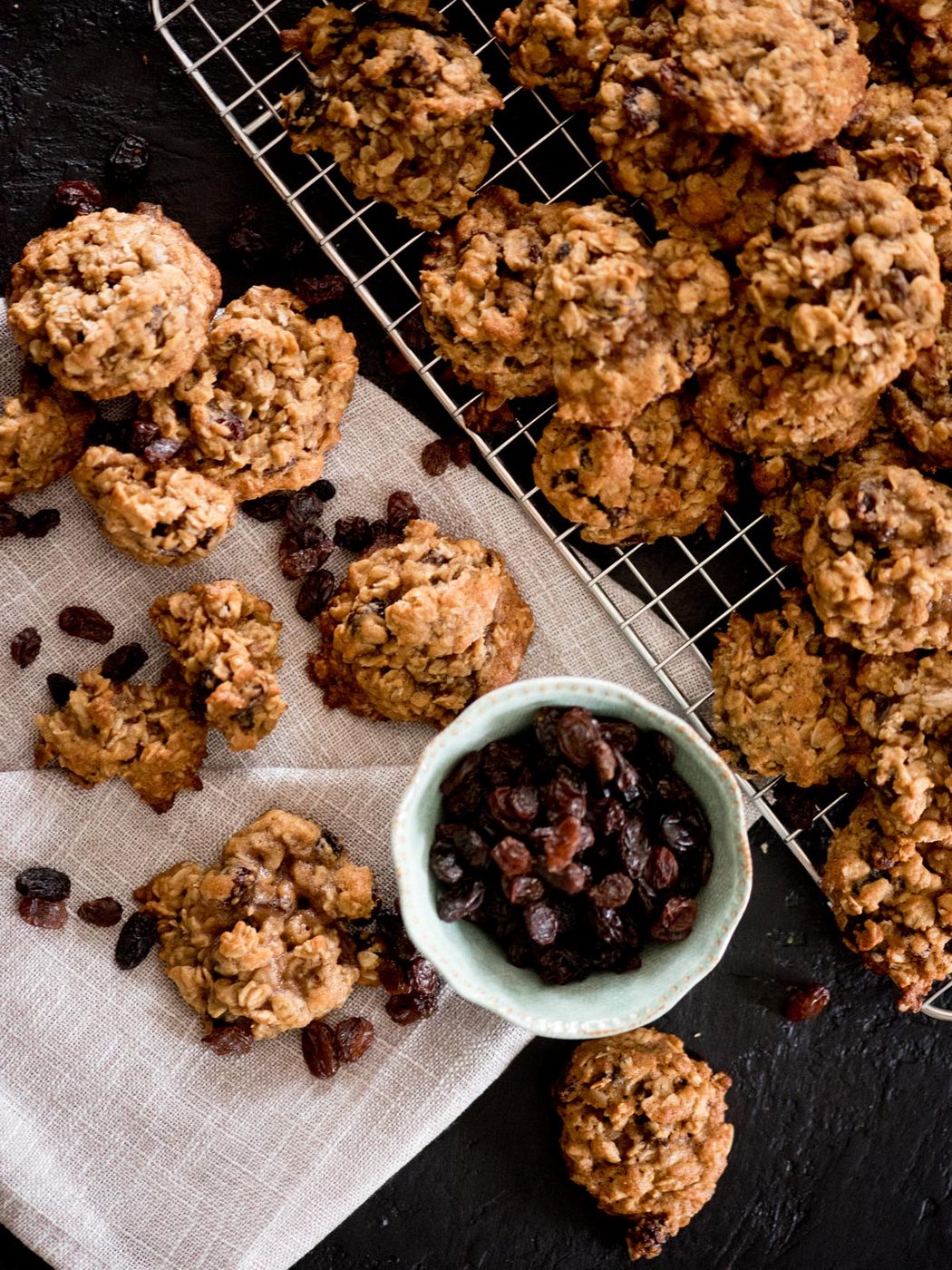 chewy oatmeal raisin cookies stacked together with extra raisins in a bowl