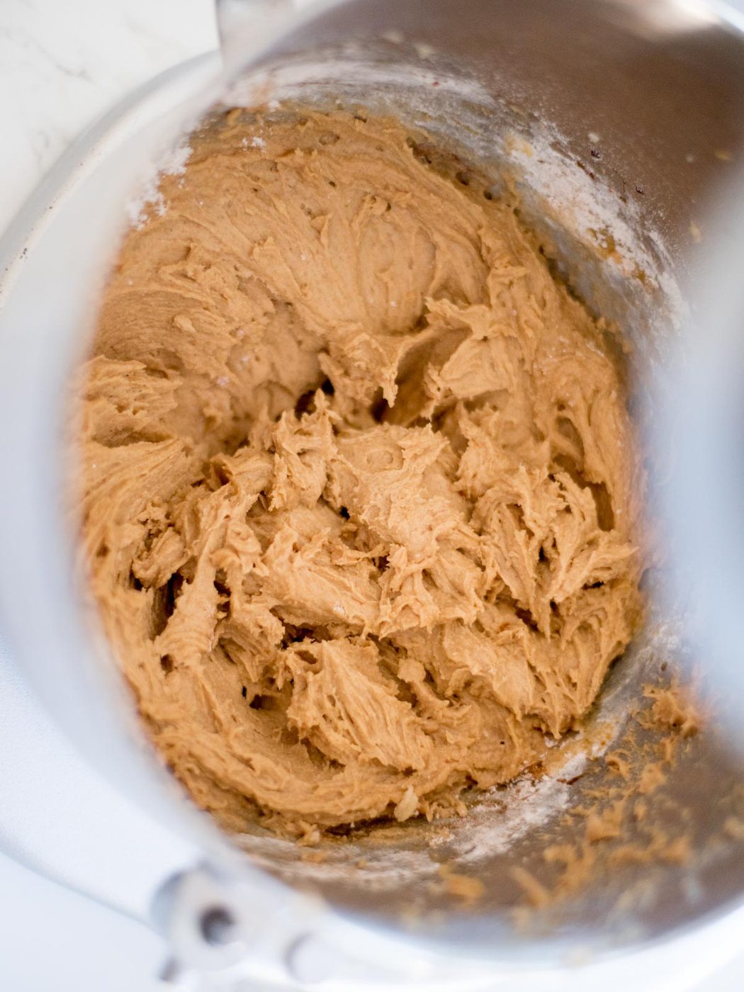 flour mixture mixed with wet ingredients inside of a mixing bowl for oatmeal raisin cookies