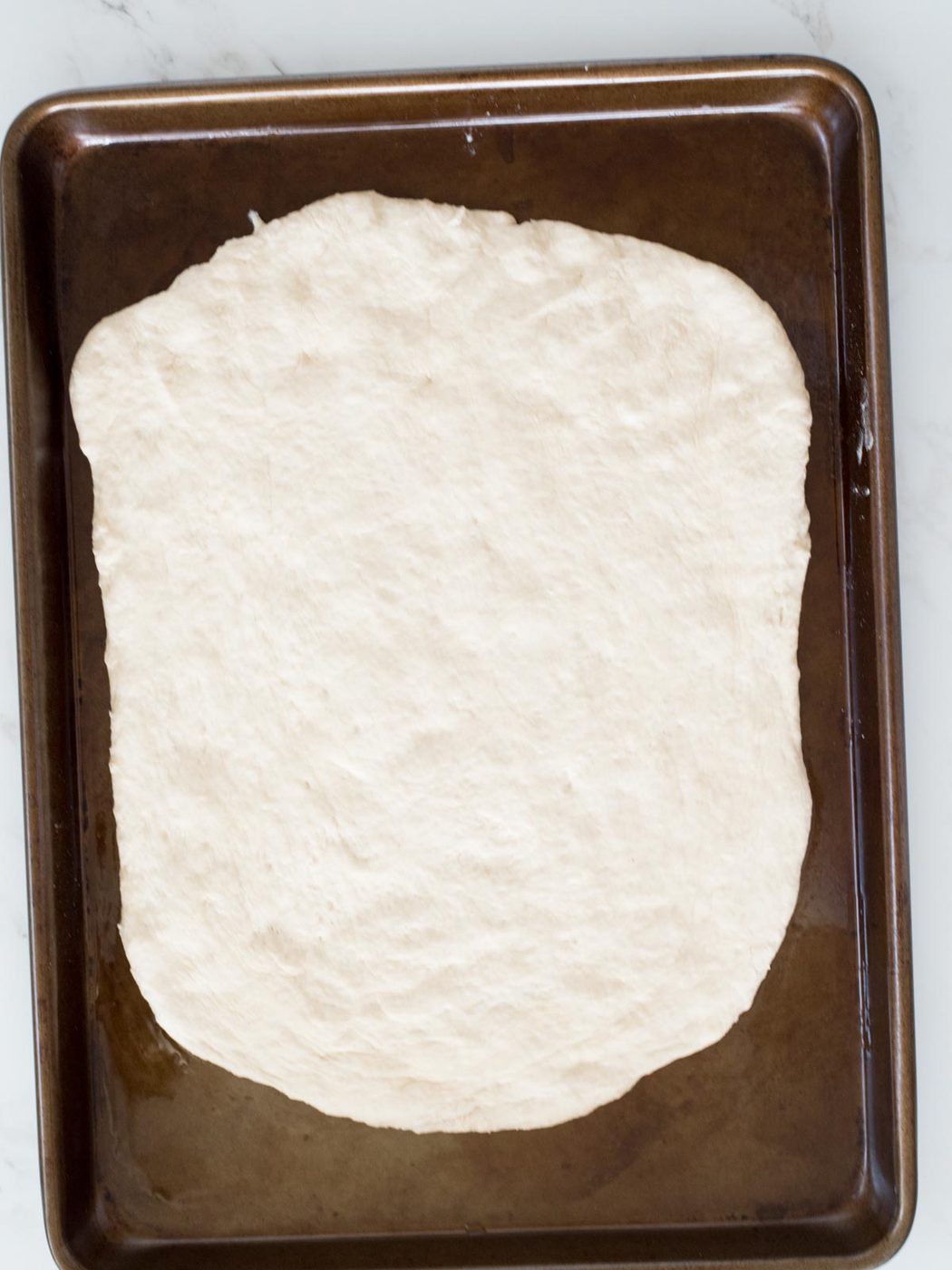 dough spread out on a baking sheet