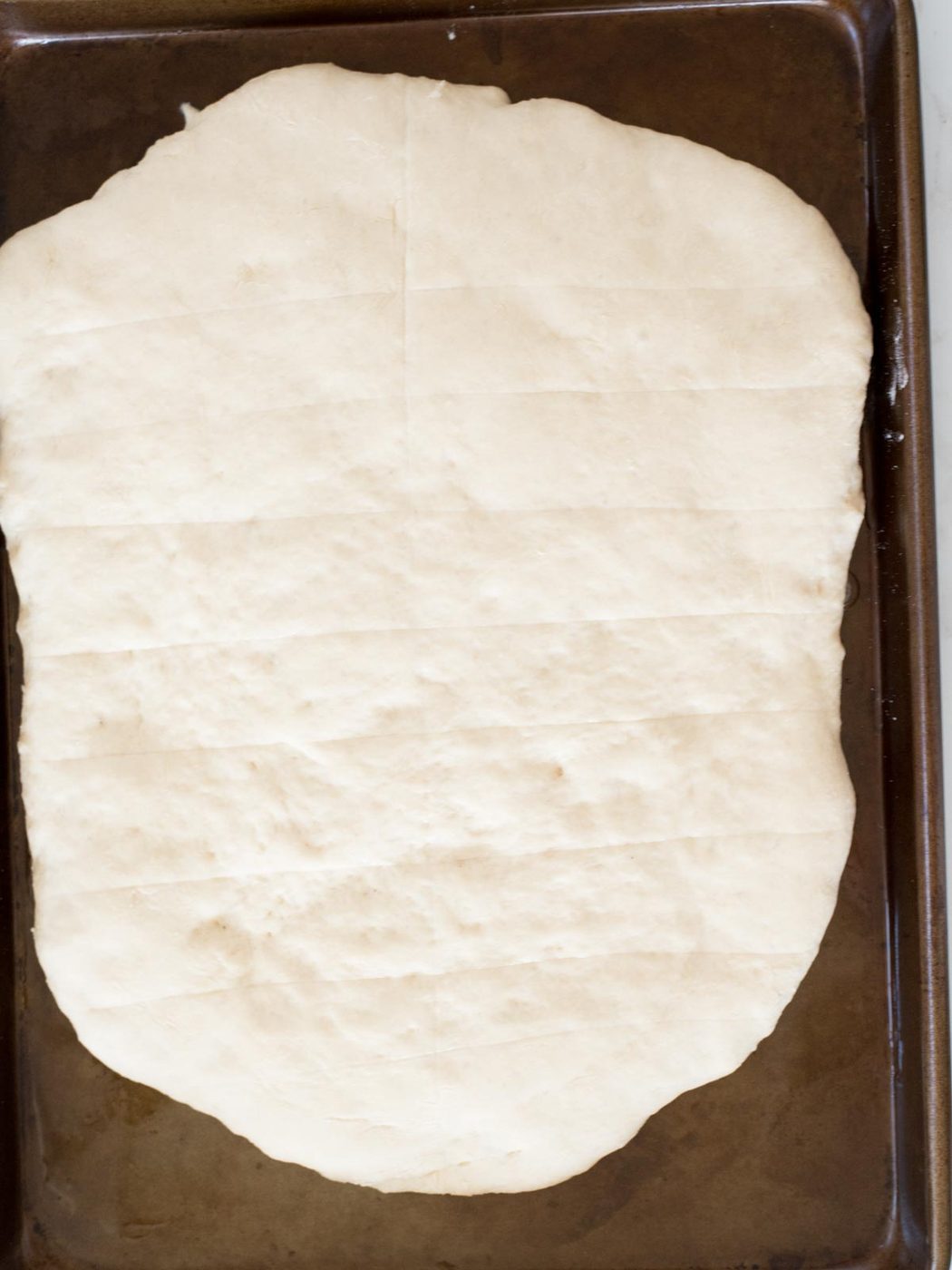 scored dough risen on a baking sheet