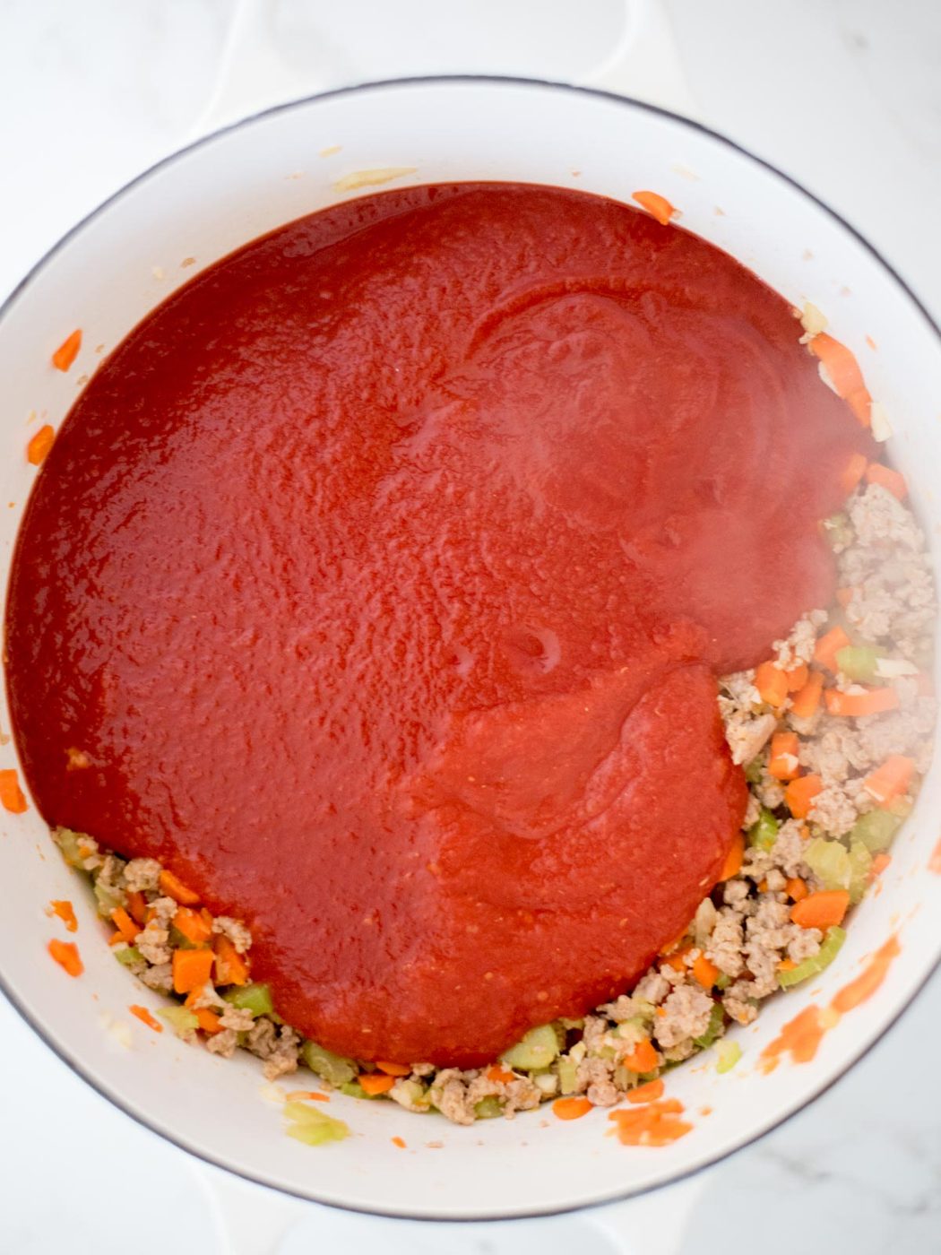 crushed tomatoes and tomato sauce added to dutch oven with sausage mix