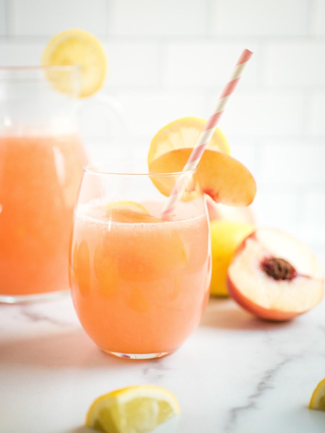 a glass of peach lemonade with a straw