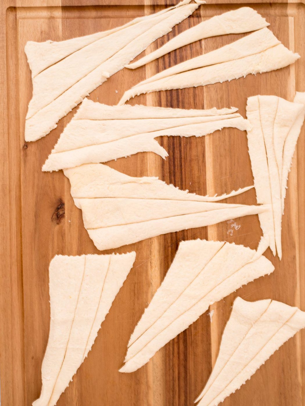 Raw crescent rolls removed from the package and placed on a cutting board.
