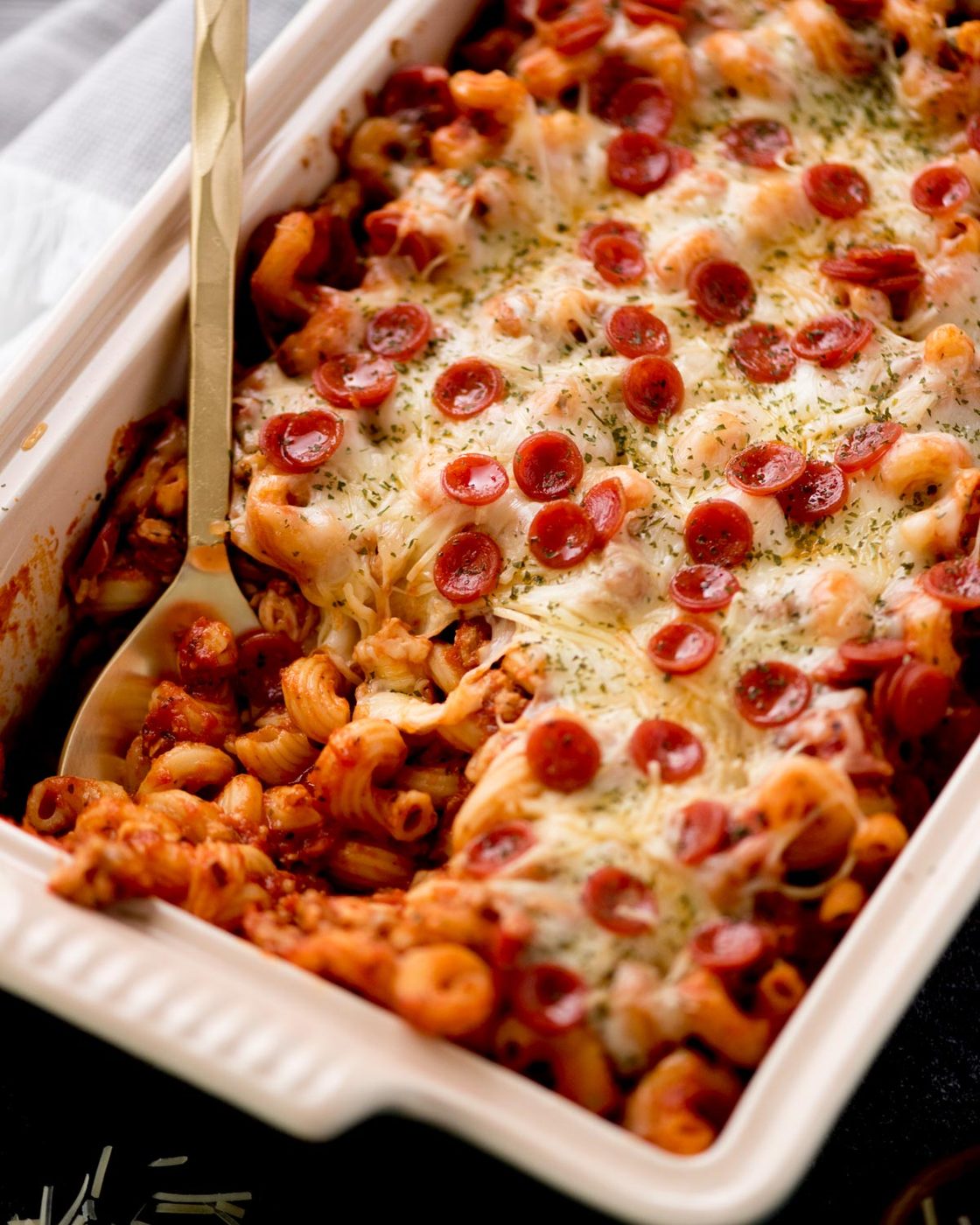 pizza casserole in a baking dish with a serving utensil inside of it