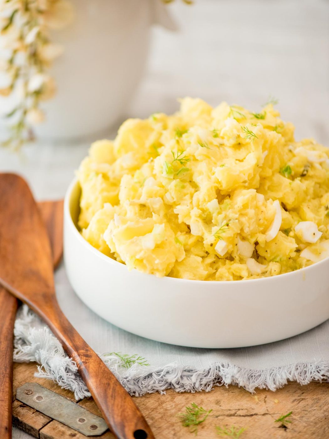 potato salad topped with fresh dill in a white bowl