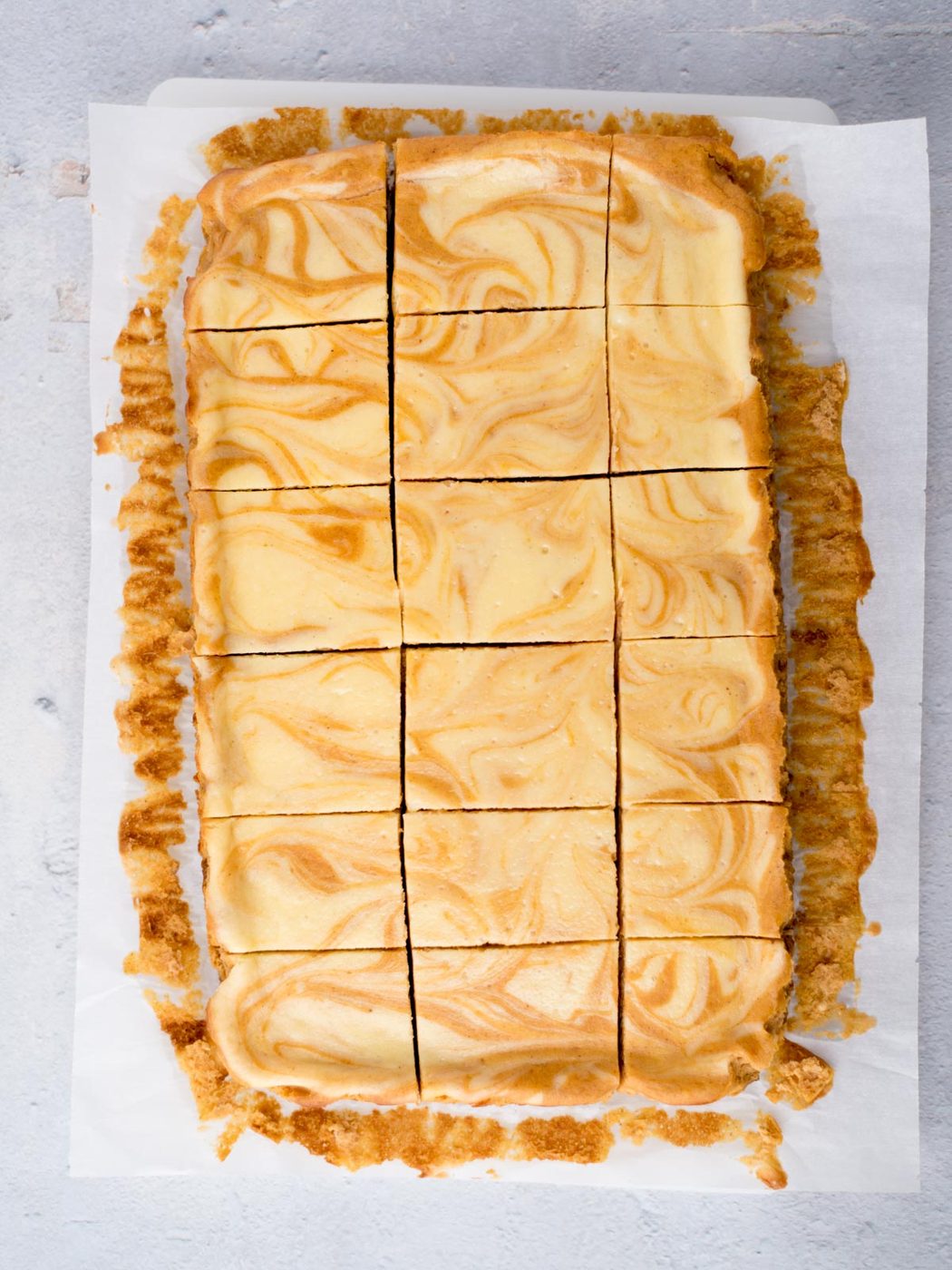 cut pumpkin cheesecake bars on parchment paper
