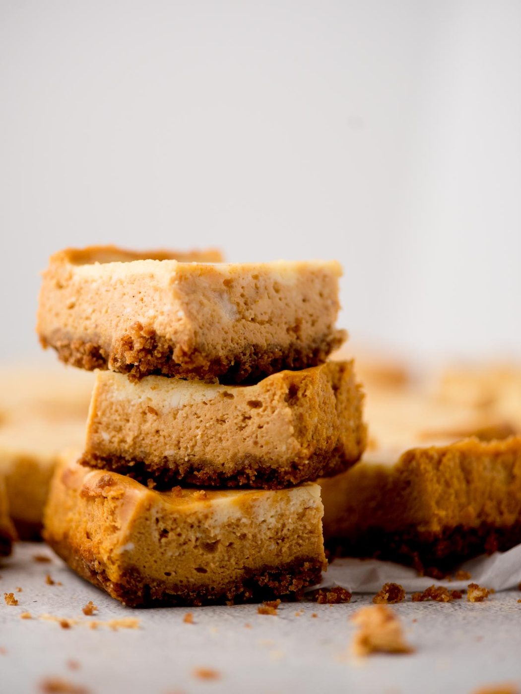 3 baked pumpkin cheesecake bars stacked on each other