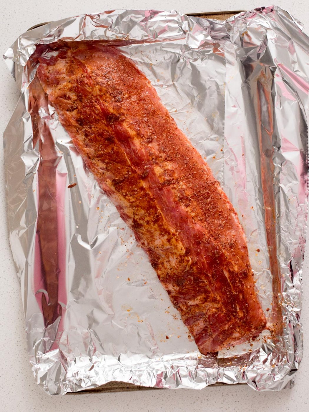 Dry rub coating ribs on an aluminum foil coated baking sheet.