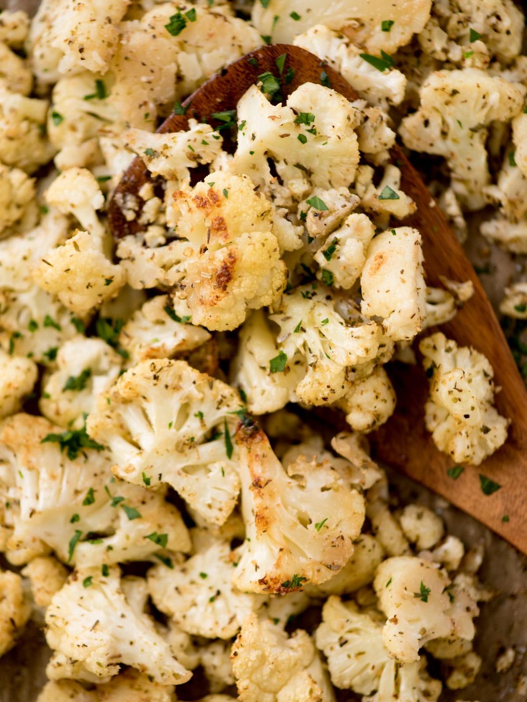 roasted cauliflower being scooped from a baking sheet