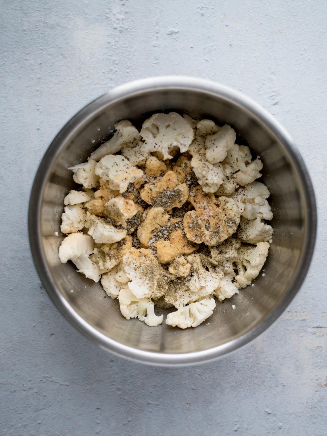 seasoned chopped cauliflower in a mixing bowl