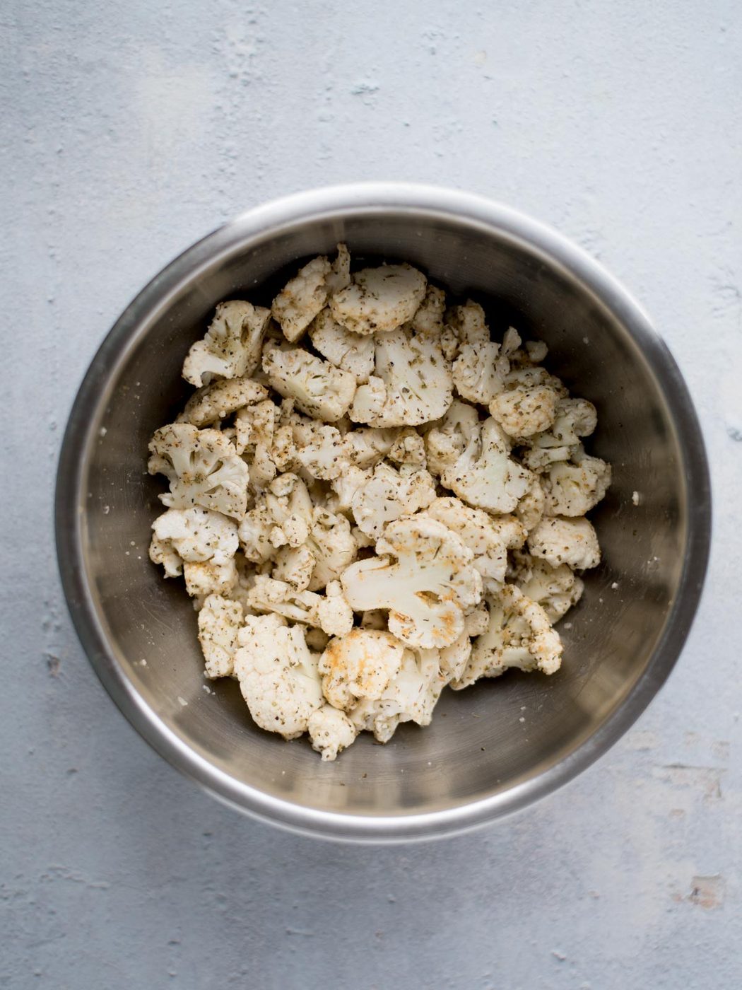 seasoned chopped cauliflower in a mixing bowl