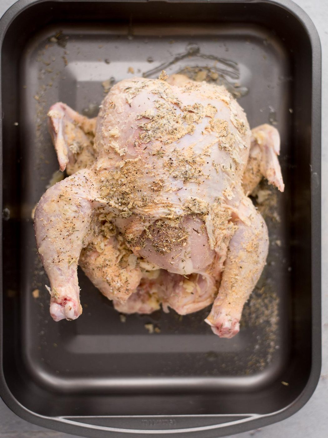 raw whole chicken covered in herb butter