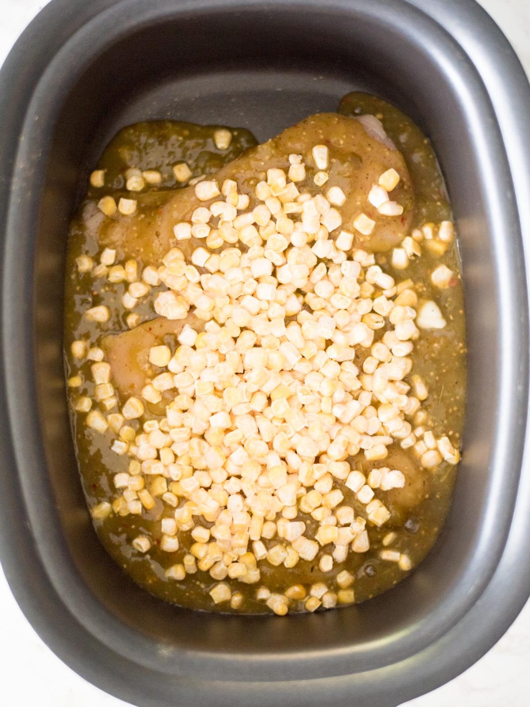 Corn added to the crockpot with the chicken and salsa verde.
