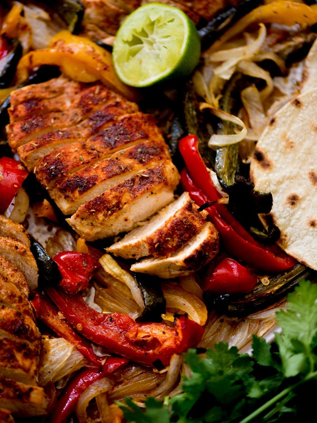 sheet pan chicken fajitas with creamy cilantro lime sauce, tortillas, and limes