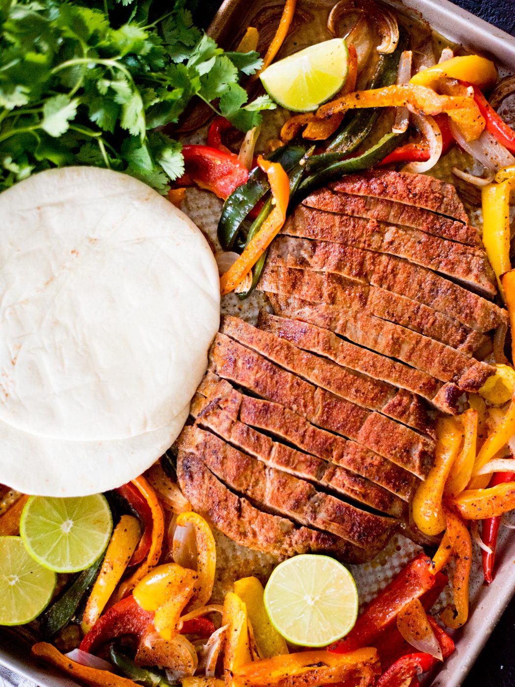 sheet pan beef fajitas with tortillas and limes