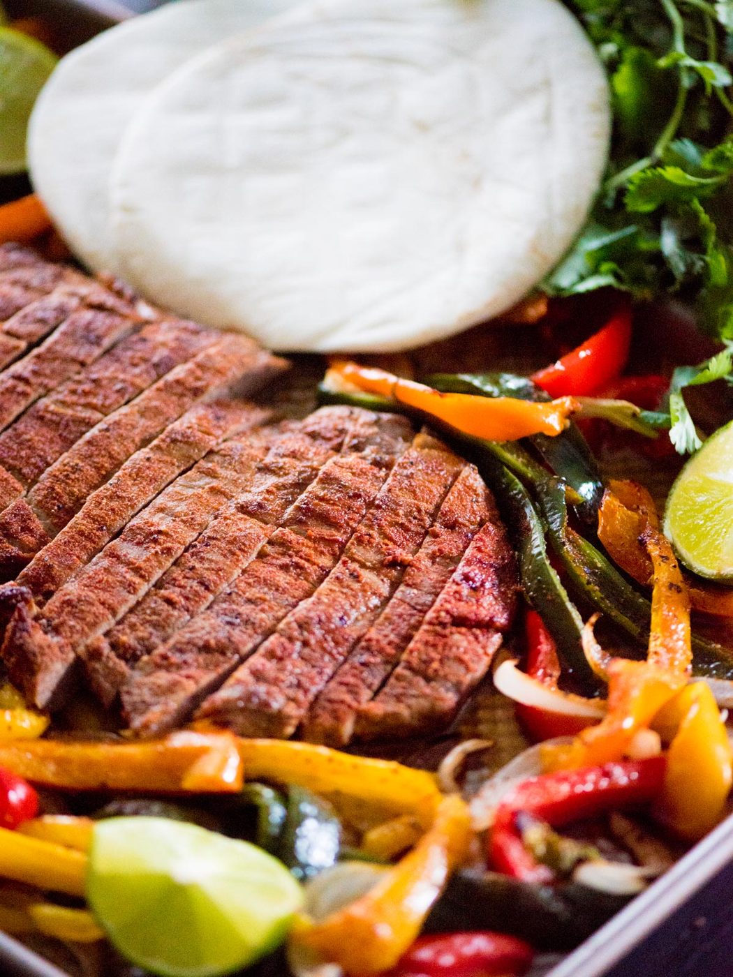 sheet pan beef fajitas with tortillas and limes