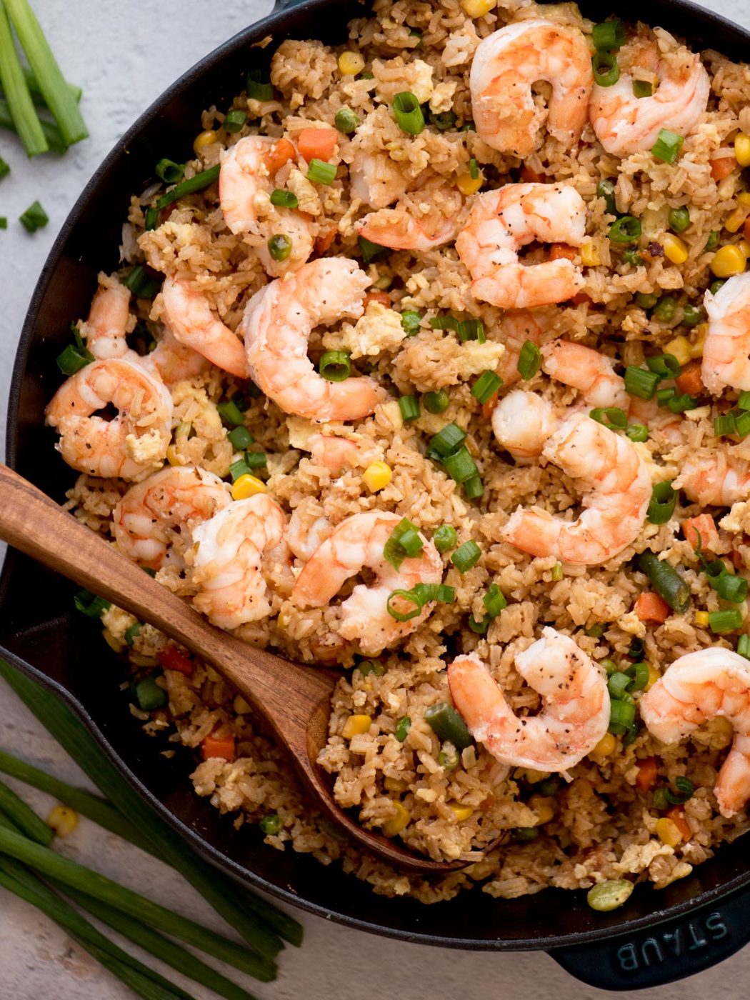 shrimp fried rice in a skillet with a wooden spoon