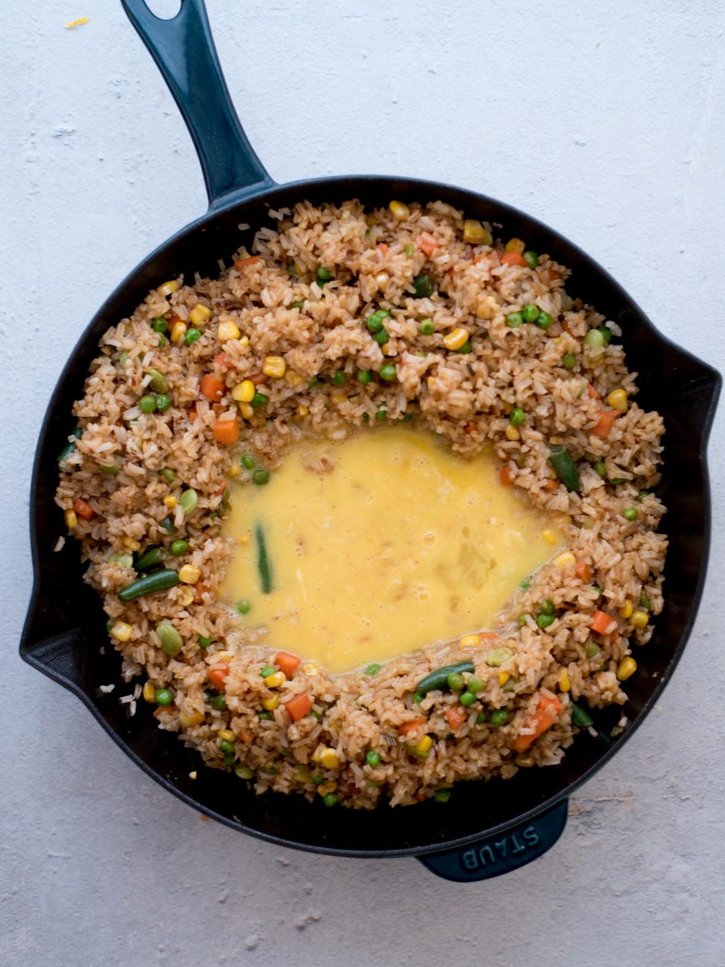 whisked eggs added to the center of the skillet with vegetables and rice