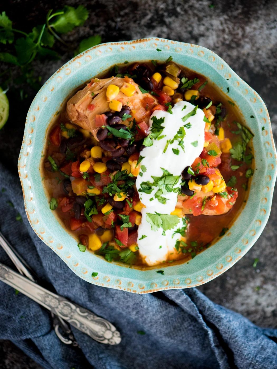 slow cooker mexican chicken in a bowl topped with cilantro and sour cream