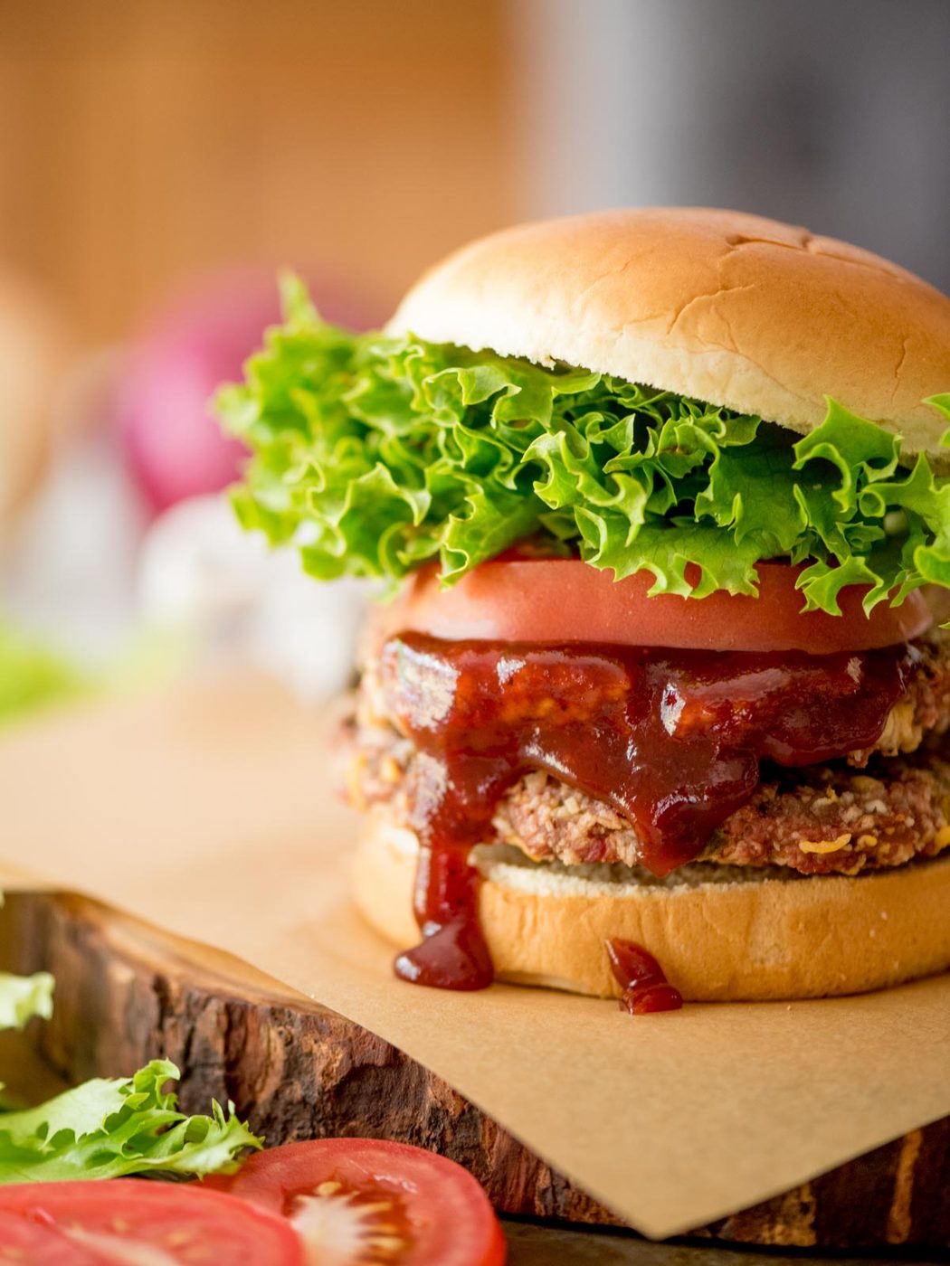 smoked burgers on a bun topped with tomatoes, lettuce, and bbq sauce