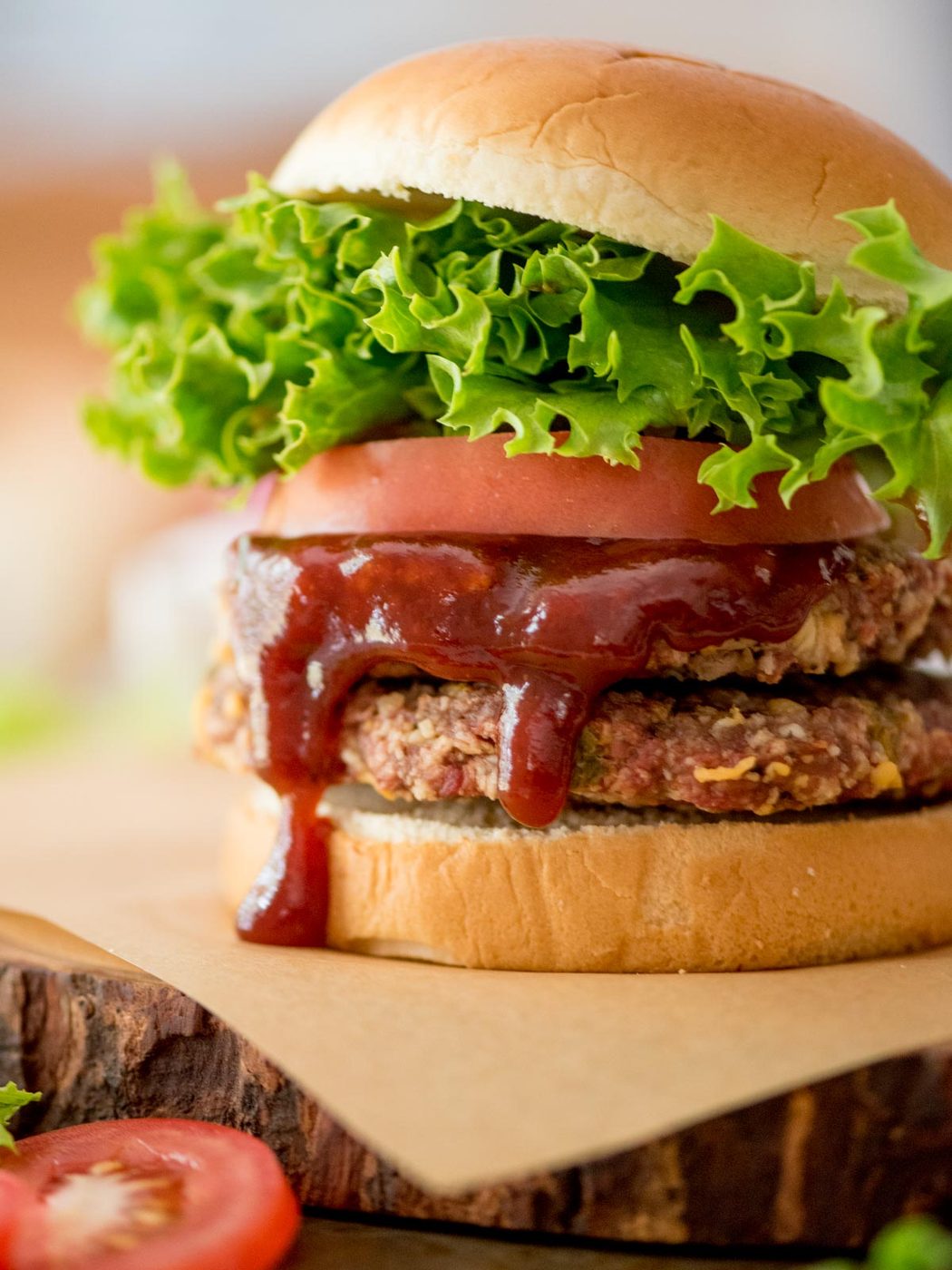 smoked burger on a bun topped with lettuce, tomatoes, and bbq sauce