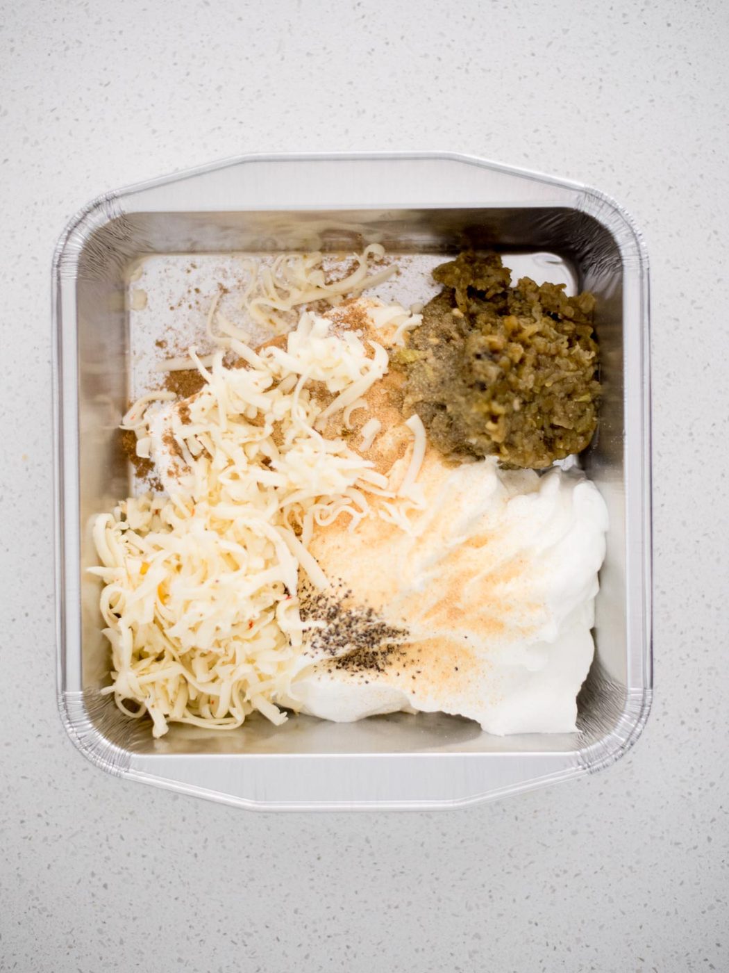 Measured ingredients for smoked queso blanco in a baking dish.