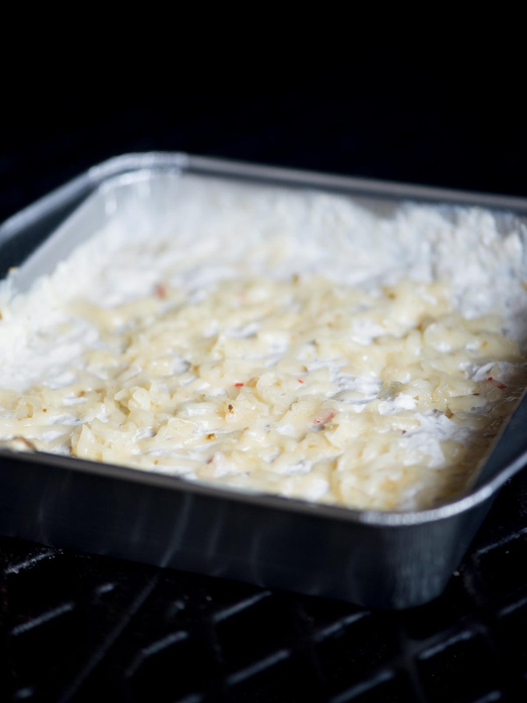 A baking dish of queso blanco in the smoker.