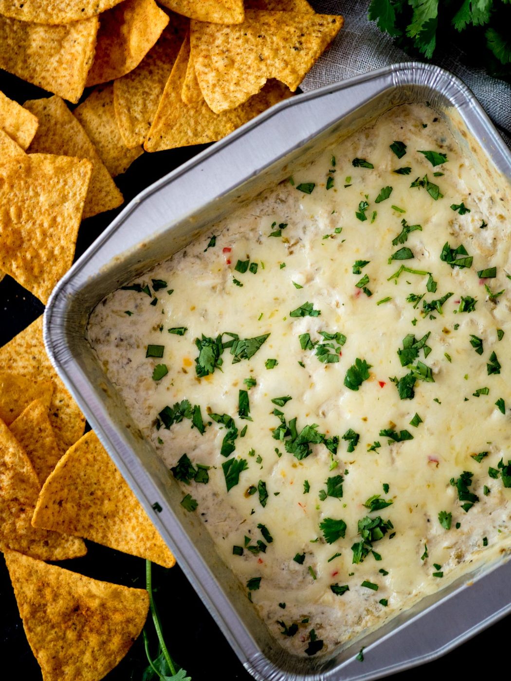 Baking dish of queso blanco next to corn tortilla chips.